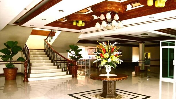 A lobby with a marble staircase, a round table with a floral centerpiece, and a chandelier. - Villa Maria Luisa Hotel (Tandag)