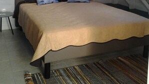 Un dormitorio con cama, almohadas, un cuadro y una ventana.