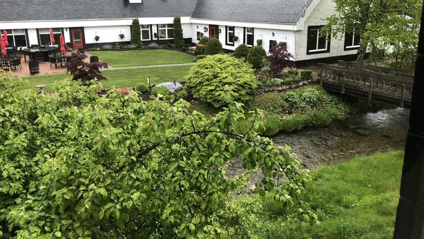 A white building with a black roof, surrounded by lush greenery and a small stream. - Summer Fun on Sandy Beach, Warm Water (Port Hood)
