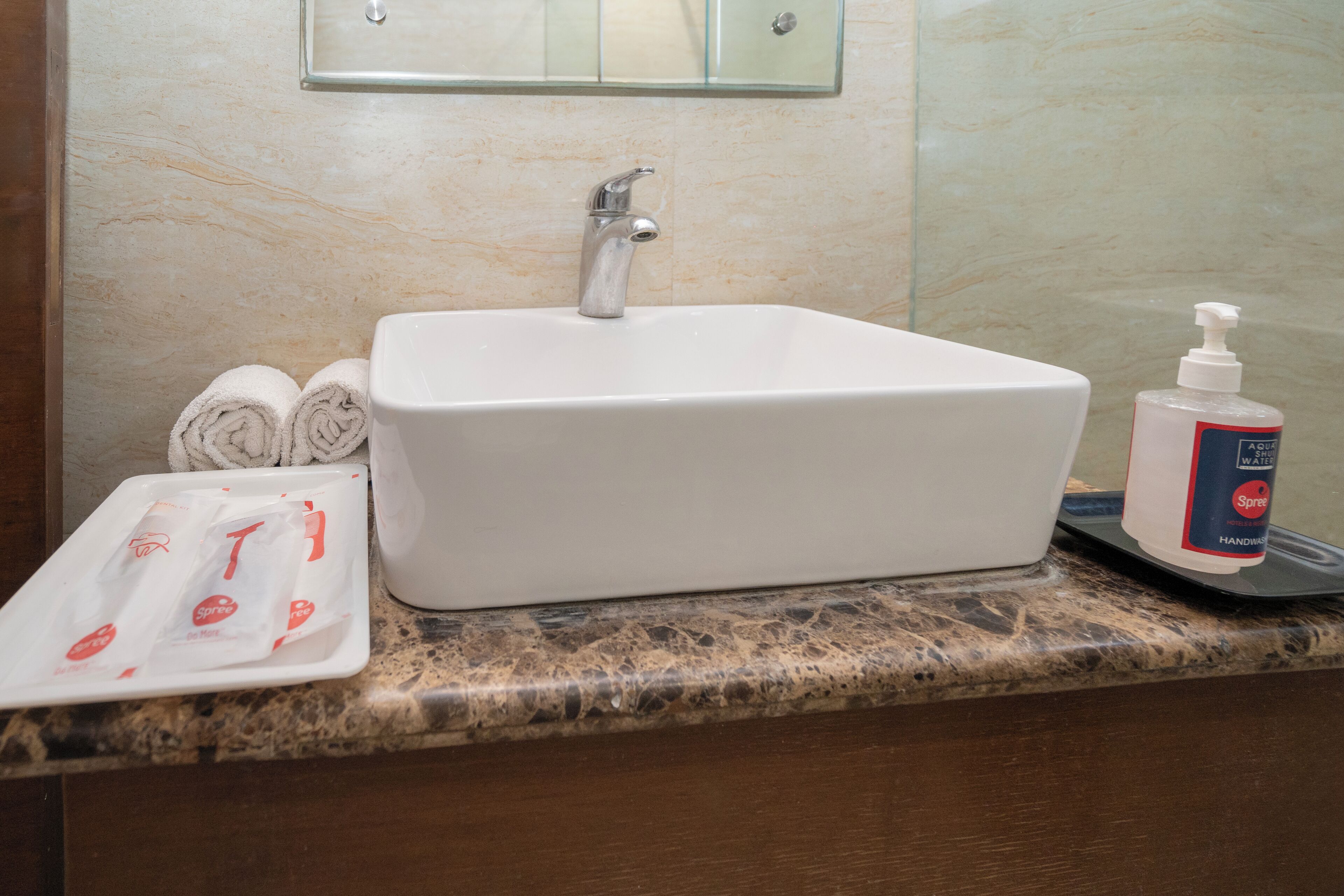 Un baño con lavamanos blanco, un espejo encima y un dispensador de jabón en la encimera.