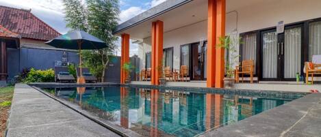 Een buitenzwembad, parasols voor strand/zwembad