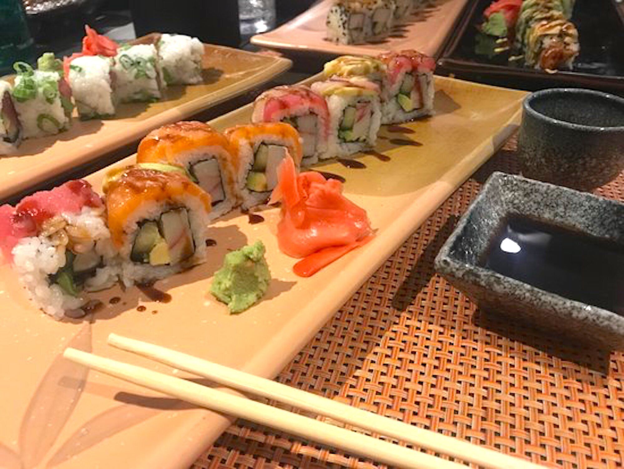 En sushi-anretning med forskellige sushityper, herunder nigiri og ruller, samt små skåle med soja og wasabi.