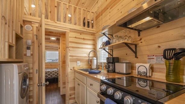 Une cuisine compacte avec des murs en bois, un lave-linge, une cuisinière et un petit évier.