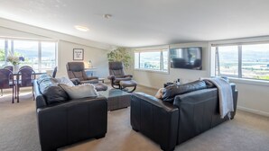 A spacious living room with a large window, a flat-screen TV, and a comfortable seating area.
