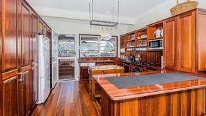 Una cocina amplia con armarios de madera, una isla central y vistas al jardín trasero a través de una puerta corrediza de vidrio.