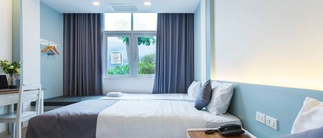A hotel room with two beds, a desk, and a window with curtains.