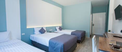 A hotel room with two beds, a desk, and a TV.