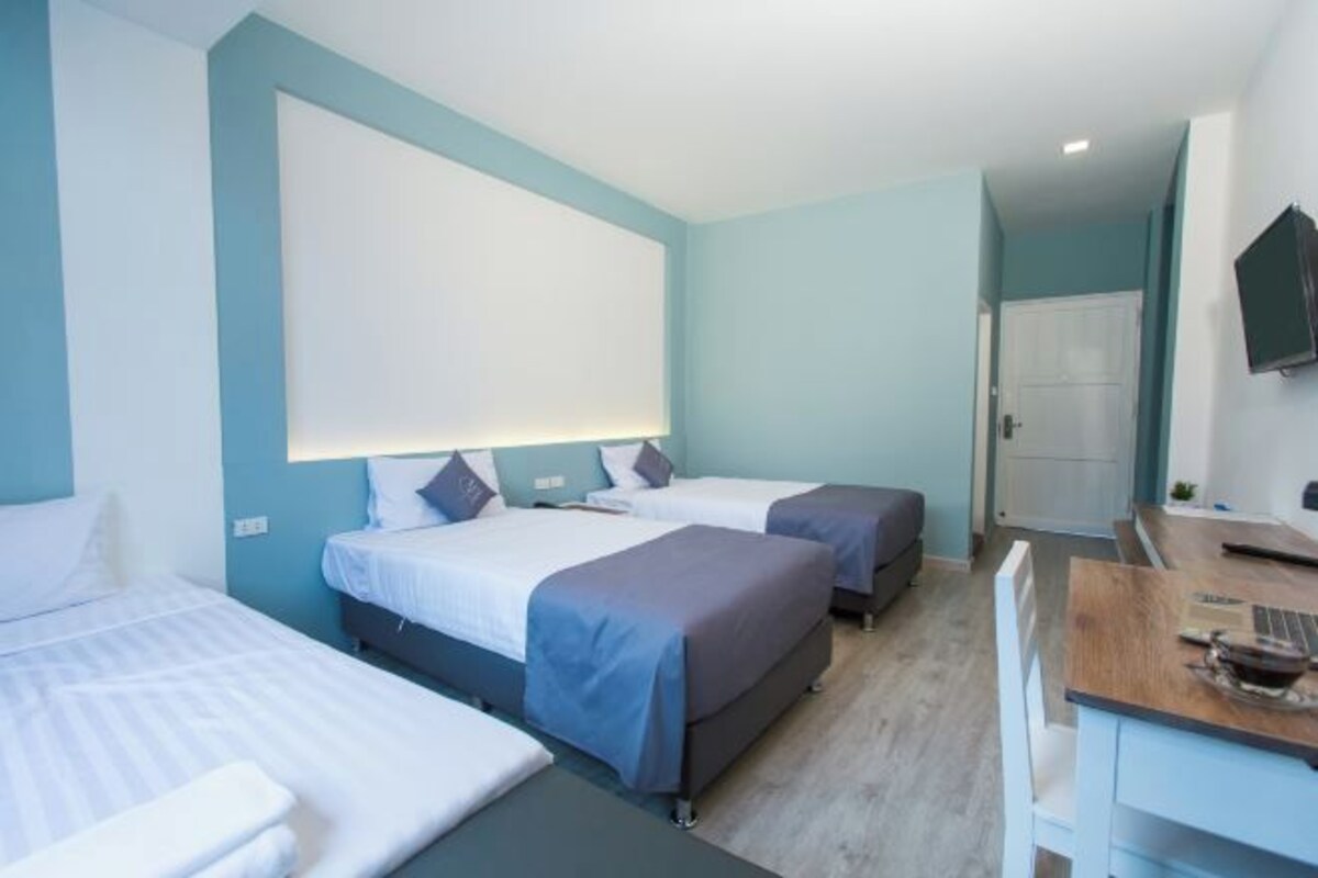 A hotel room with two beds, a desk, and a TV.