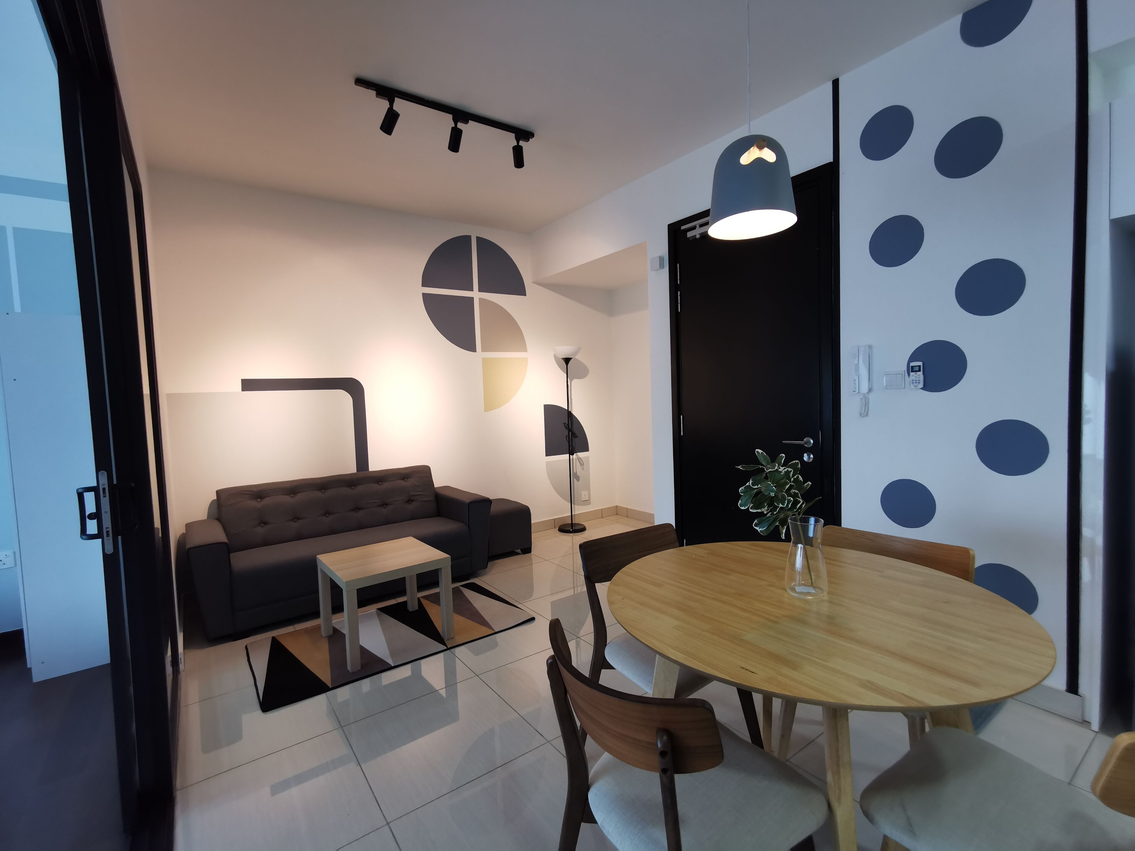 A modern living room with a sofa, a coffee table, and a dining area with a round table and chairs.
