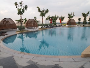 Una piscina con sillas de descanso y palmeras.