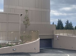 A modern building with a metal facade, a gated entrance, and a no parking sign.