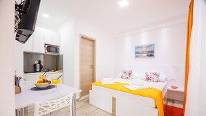 Moderni hotellihuone, jossa on sänky, ruokapöytä, mikroaaltouuni ja taulu seinällä.