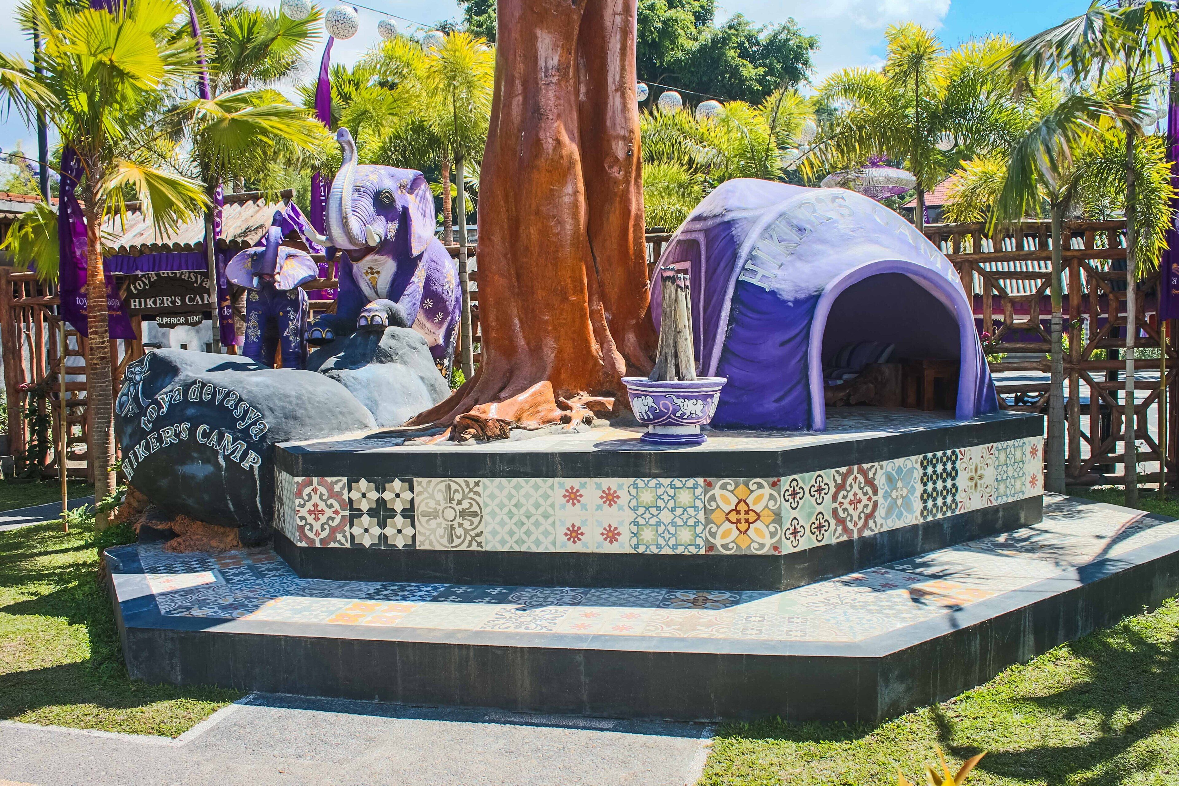 A stage with a large tree, a tent, and a decorative bowl.