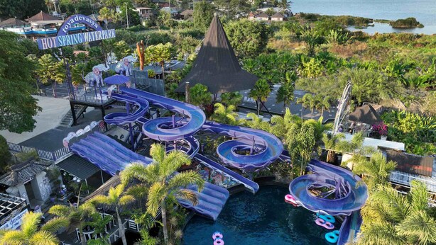 A water park with multiple slides and a pool area surrounded by palm trees. - Hiker's Camp at Toya Devasya (Kintamani)