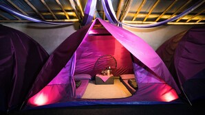 A tent with a central sleeping area, a small table with bottles, and a canopy overhead. - Hiker's Camp at Toya Devasya (Kintamani)