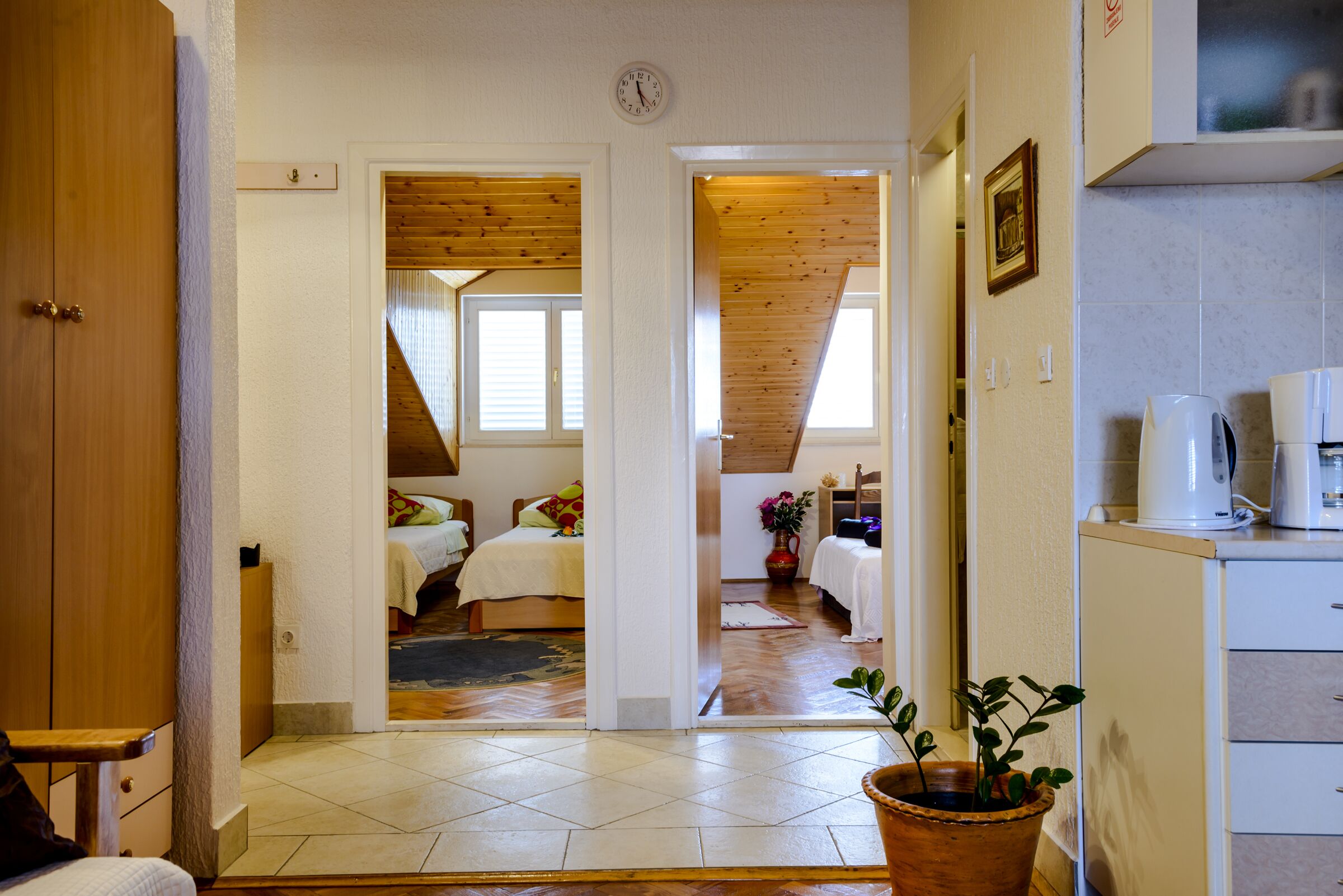 Une pièce comprenant un lit, un plafond en bois, une plante en pot et un coin cuisine avec une machine à café.