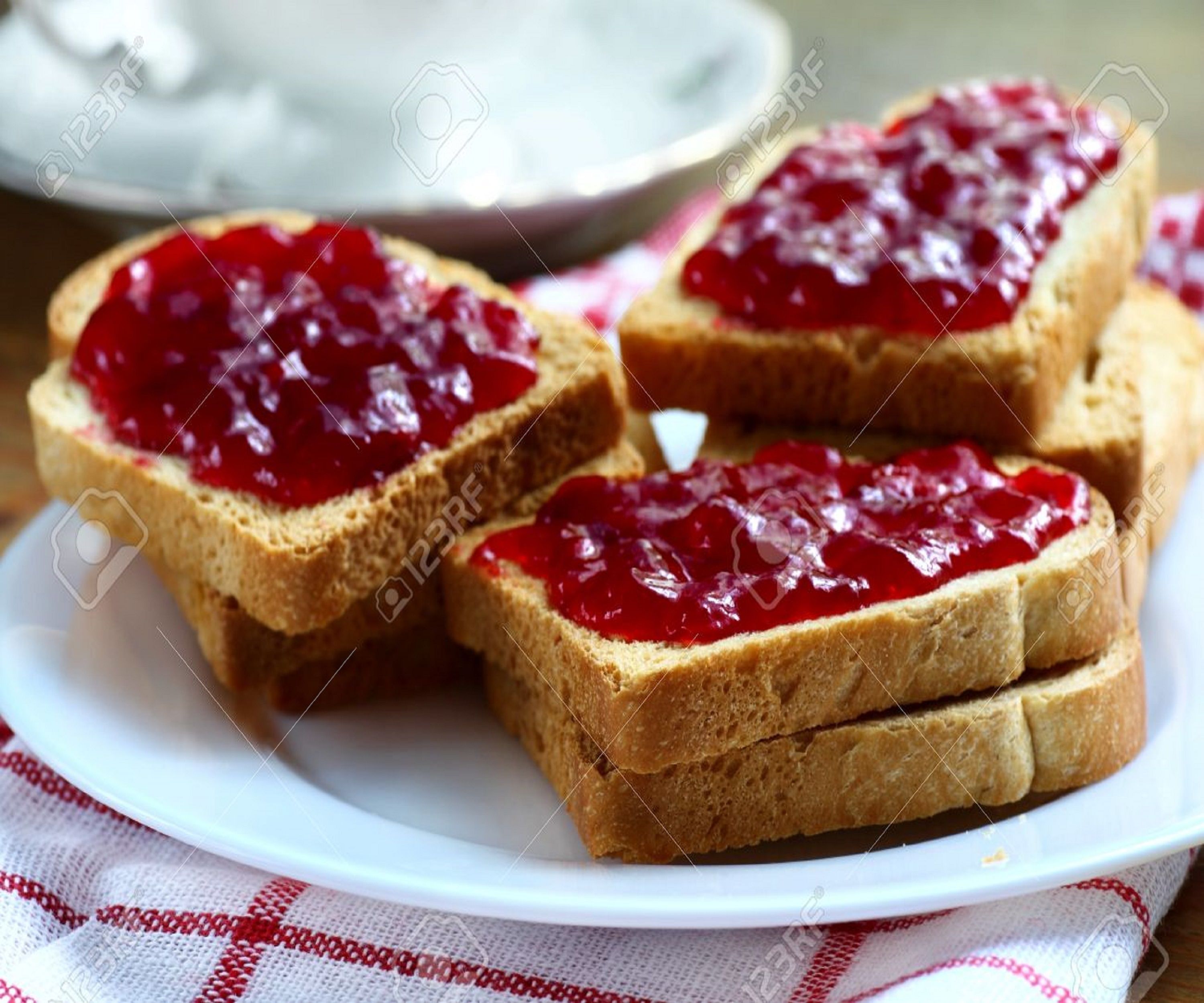 Cuatro rebanadas de tostada con mermelada sobre un plato blanco.