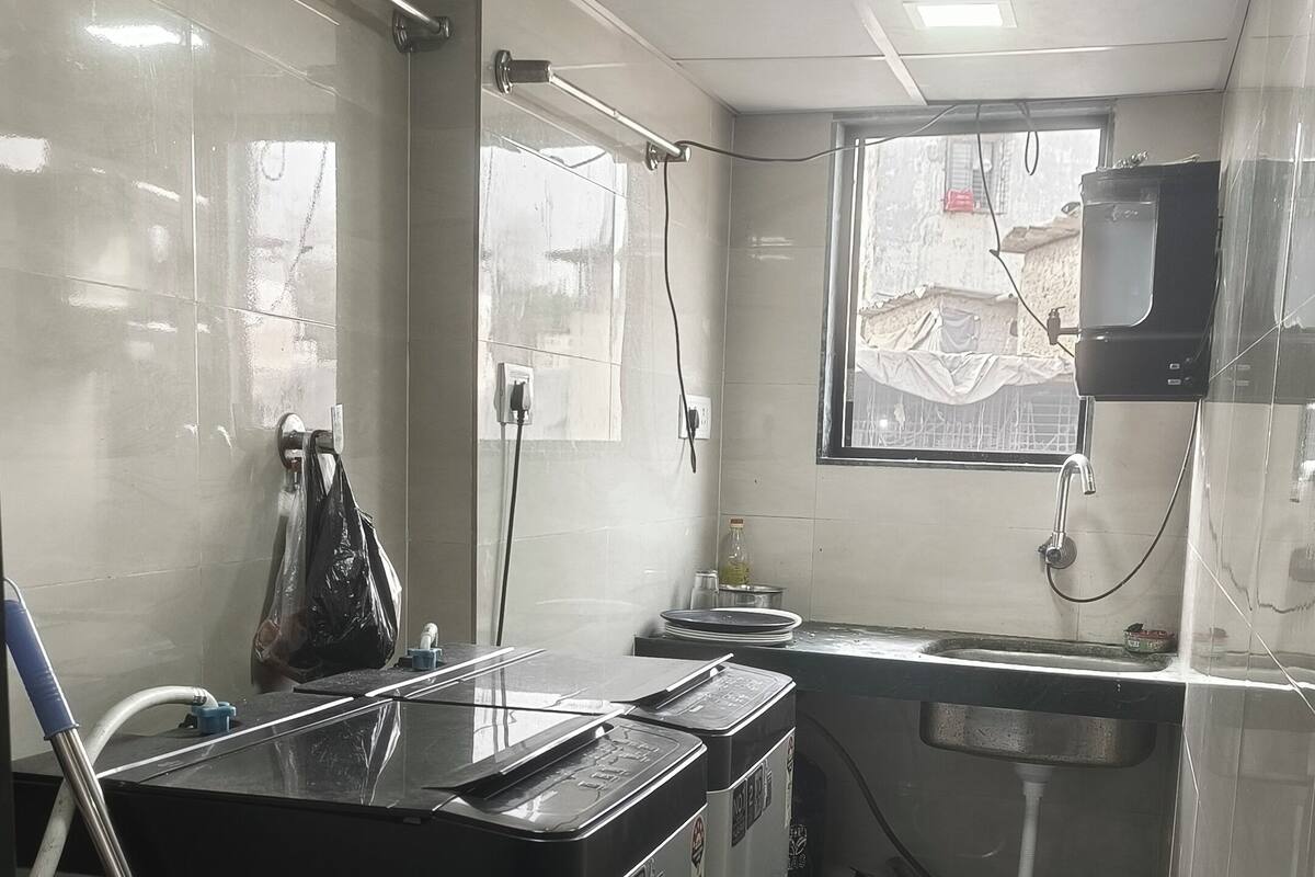 Une cuisine de taille réduite, dotée d’un sol carrelé, d’un évier, d’une fenêtre et d’un distributeur d’eau.