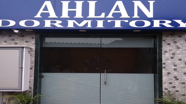 A building with a sign reading "AHLAN DORMITORY".