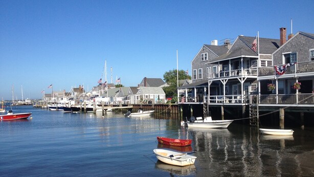 A waterfront property with a dock, boats, and a building with a balcony.