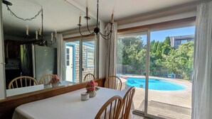 A dining area with a table, chairs, a chandelier, and a view of a swimming pool.