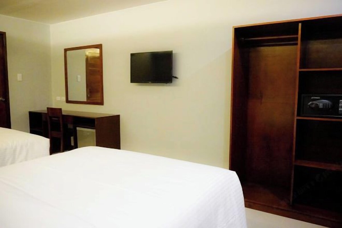Une chambre d’hôtel avec deux lits, un bureau, une télévision et une armoire.