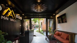 A reception area with a black reception desk, a sofa, and a decorative ceiling light. - Mai Villa & Apartment (Da Nang)
