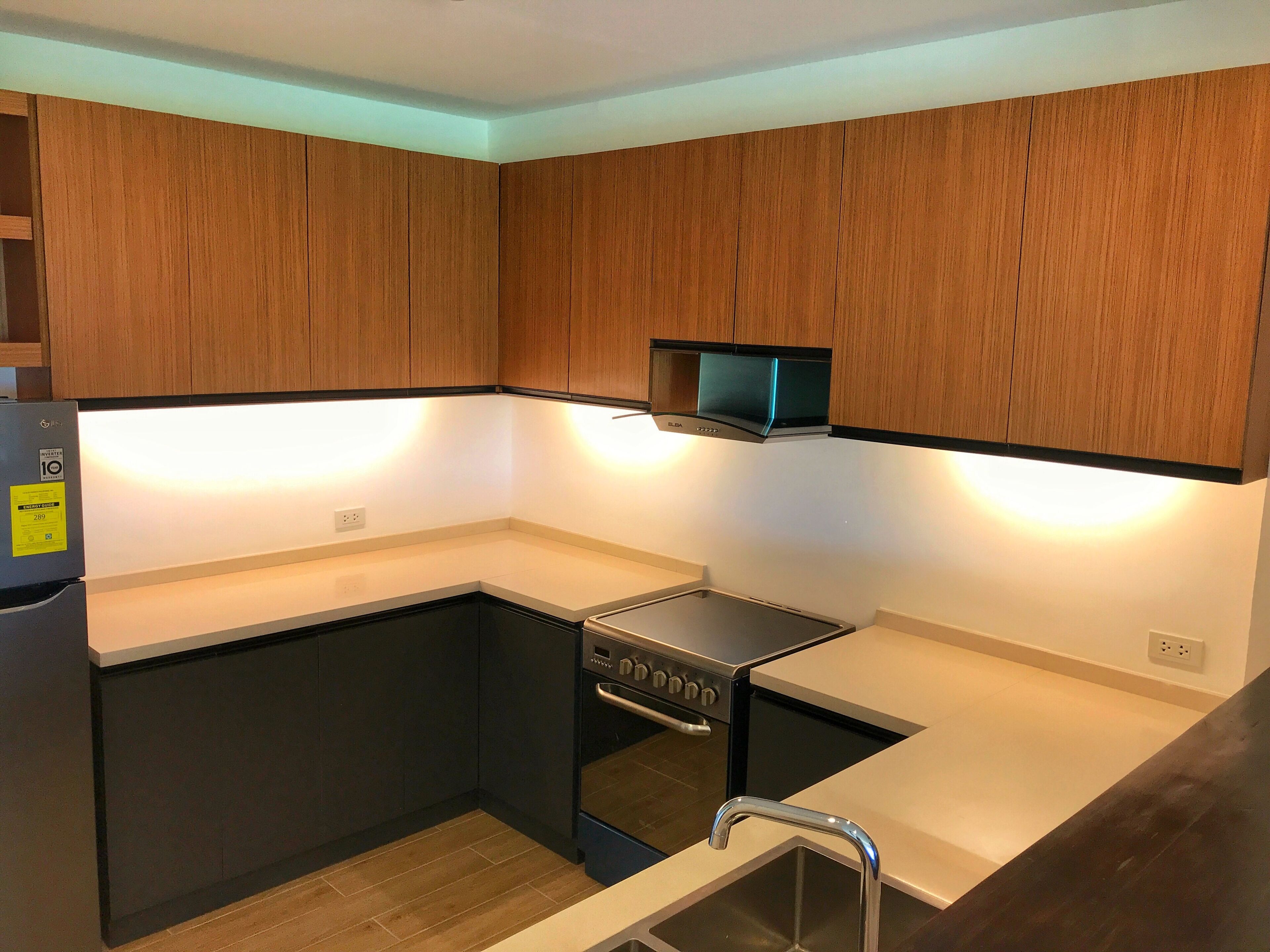 A modern kitchen with wooden cabinets, a built-in microwave, and a stainless steel oven.