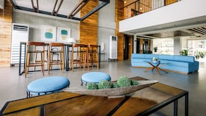 A spacious lobby with a blue sofa, wooden chairs, and a coffee table with decorative plants.