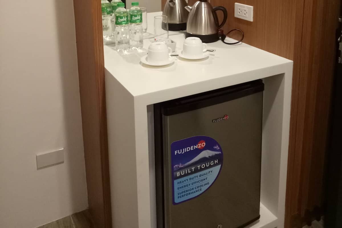 Una kitchenette compacta con una cubierta de encimera blanca, una tetera de acero inoxidable, una cafetera y un refrigerador con la etiqueta 'Fujidenzo'.