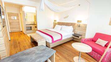 Ein modernes Hotelzimmer mit einem Bett, einer roten Couch, einem kleinen Tisch und Holzboden.