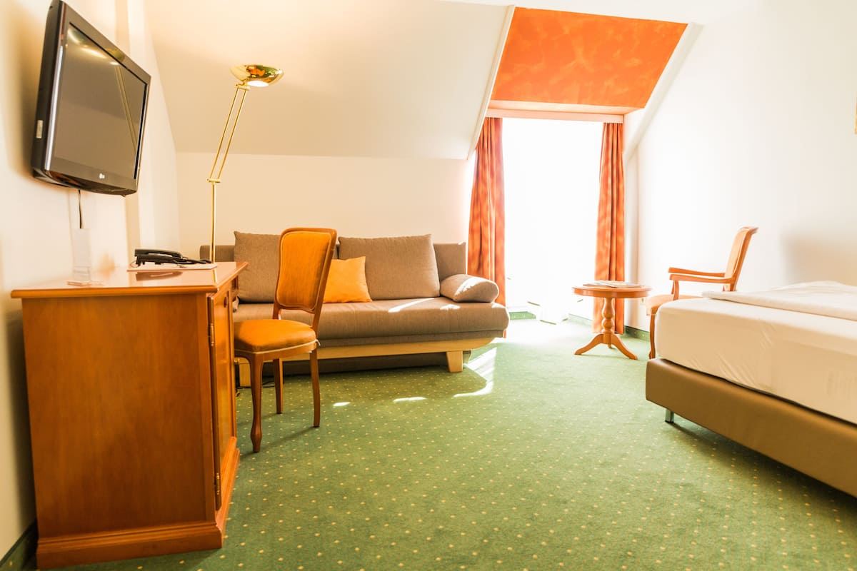 Habitación de hotel con sofá, escritorio, silla, cama y televisor.