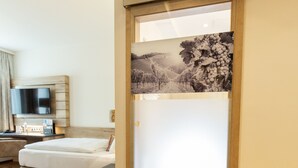 Habitación de hotel moderna con cama, televisor de pantalla plana y piso de madera.