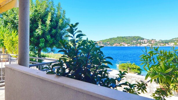 Une vue sur la côte, avec une mer bleue et limpide, une balustrade en pierre et une végétation luxuriante.
