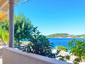 Une vue sur la côte, avec une mer bleue et limpide, une balustrade en pierre et une végétation luxuriante.