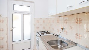 Une cuisine avec des armoires blanches, un évier en acier inoxydable et une cuisinière à gaz.