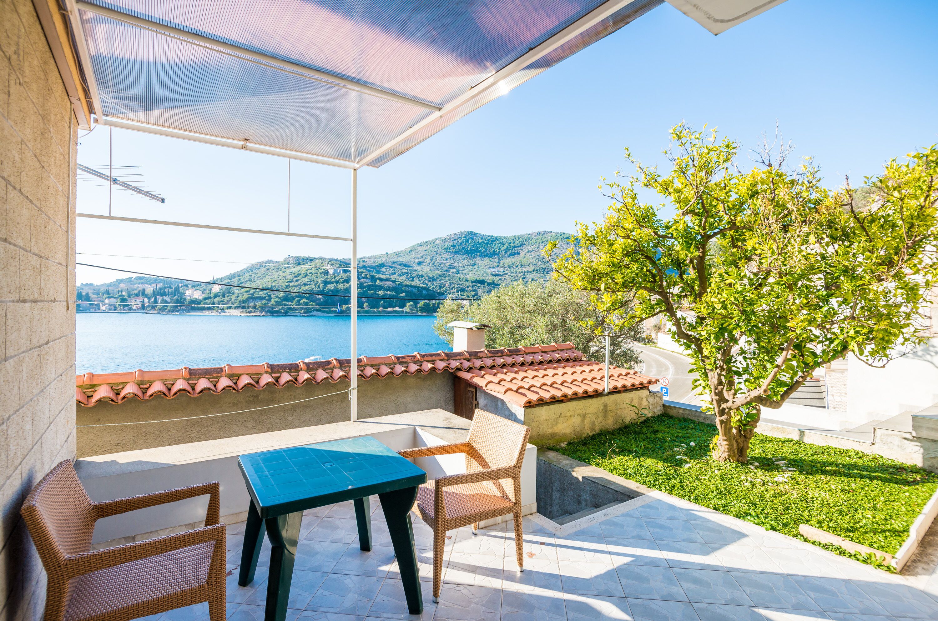 Ein Balkon mit Tisch und Stühlen mit Blick auf ein Gewässer und Hügel.