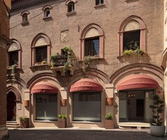 Un edificio con finestre ad arco e balconi decorati con piante. Sono presenti ampie finestre e porte, e la facciata è in mattoni.
