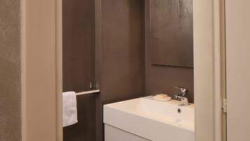 Een moderne badkamer met een grote spiegel, een wit wastafelmeubel en een handdoek aan een rek.