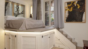 Un dormitorio con cama empotrada, escalera y ventana con cortinas.