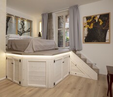 Una camera da letto con un letto a scomparsa, una scala e una finestra con tende.