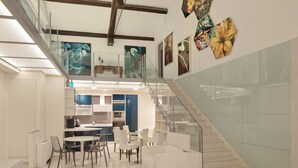 Un interior moderno con una escalera, zona de comedor y obras de arte en las paredes.