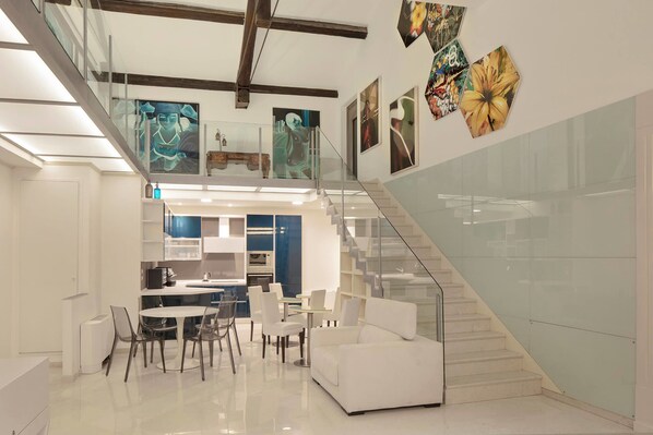 Un interior moderno con una escalera, zona de comedor y obras de arte en las paredes.