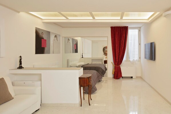 Un dormitorio moderno con cama, mesitas de noche, escritorio y un espejo grande.
