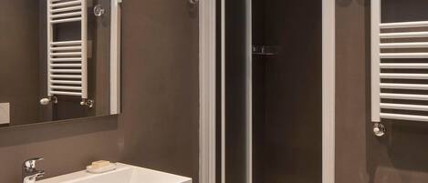 A modern bathroom with a large vanity, a glass shower enclosure, and a toilet.