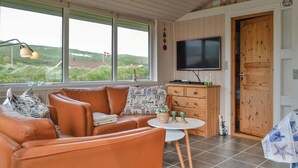 A cozy living room with a leather sofa, a small table, and a TV mounted on the wall. - Cozy home in Hvide Sande with kitchen (Hvide Sande)