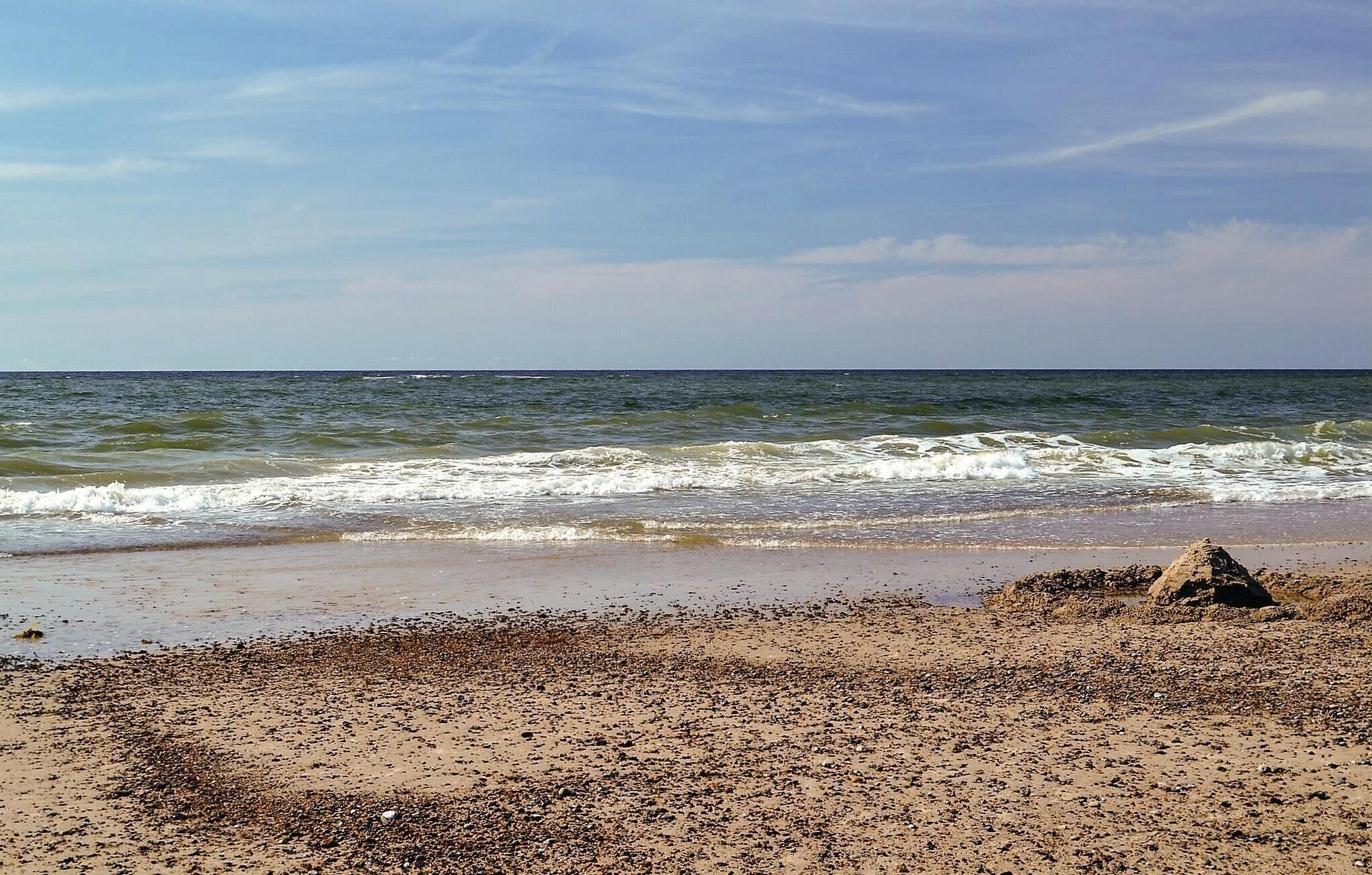 A beach with pebbles and a sandcastle.