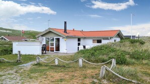 A small, single-story building with a red-tiled roof, a chimney, and a door leading to an interior space. - Cozy home in Hvide Sande with kitchen (Hvide Sande)