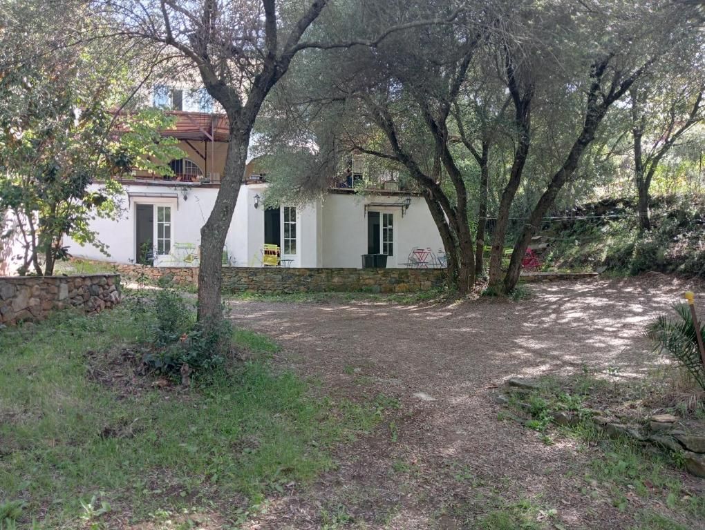 Un edificio blanco con base de piedra, rodeado de árboles y un área con césped.
