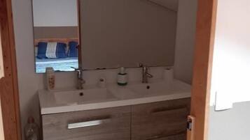 A bathroom with a double sink, wooden vanity, and a mirror.